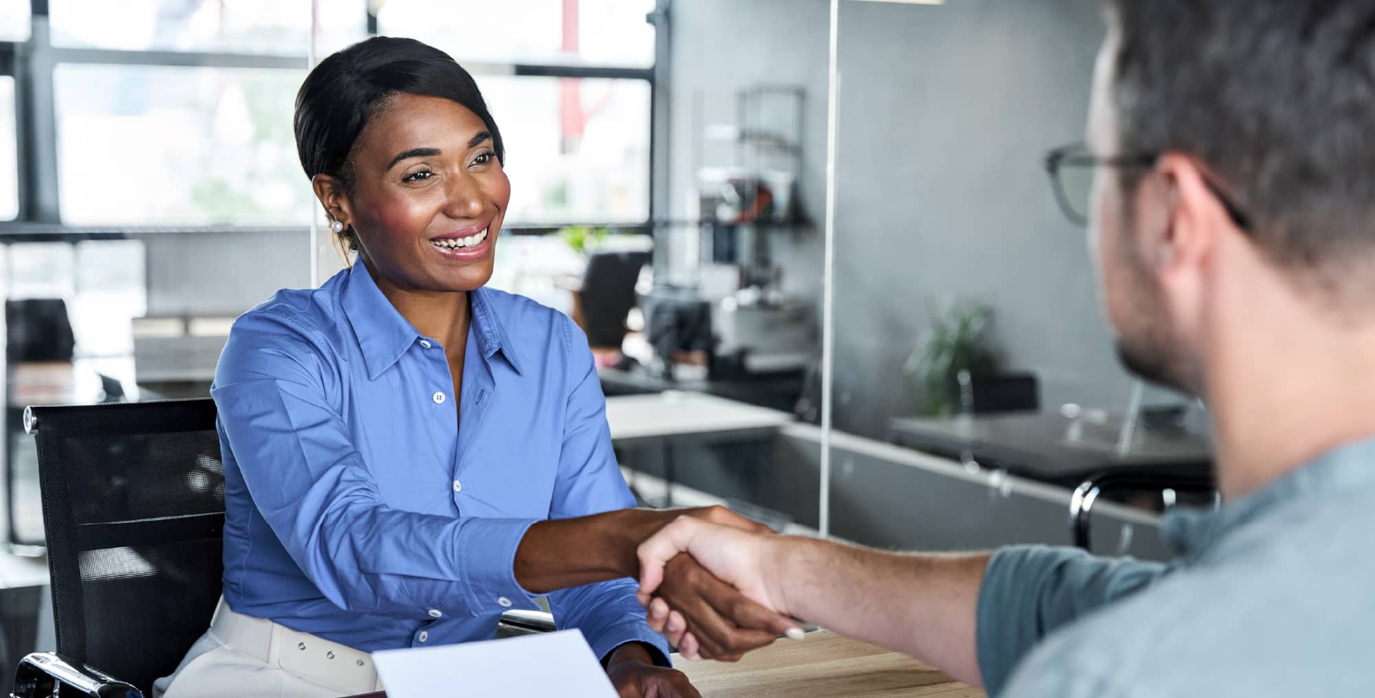Photo of a woman shaking hands with a candidate representing the completion of a behavioral interview